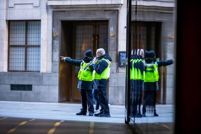 Two security guards in high vis pointing down a London street